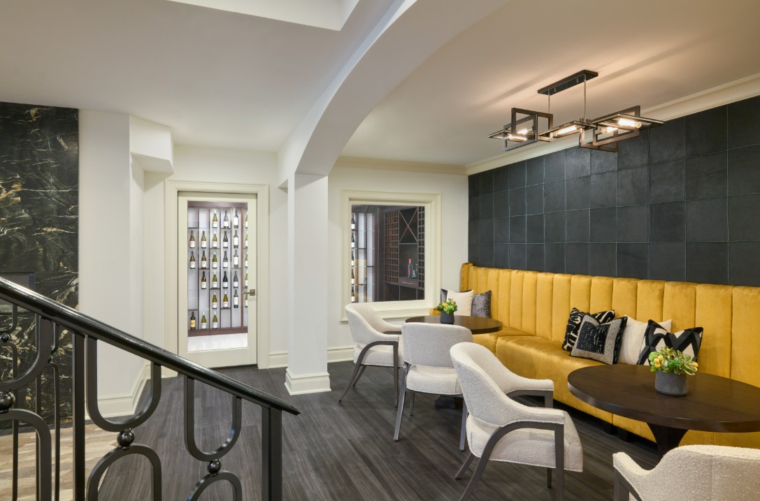 Luxury wine tasting lounge featuring golden velvet banquette, boucle chairs, and leather-paneled accent wall for rich textural contrast.