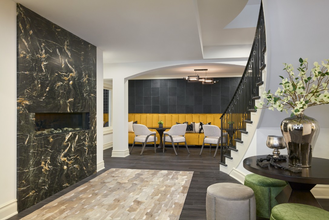 Striking entry to wine lounge featuring dark marble fireplace, golden banquette seating, and a modern blend of layered materials.
