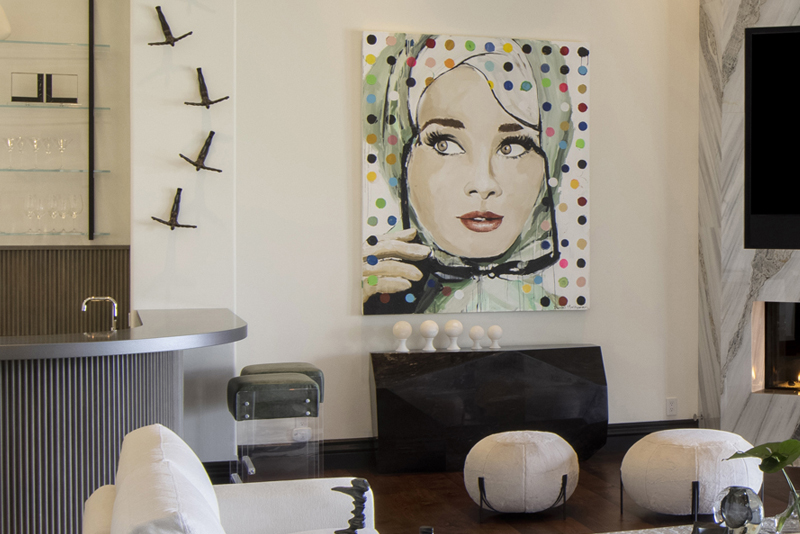 Bold pop art wall piece with polka dots inspiring cohesive interior design in a modern living room with circular poufs and bar area