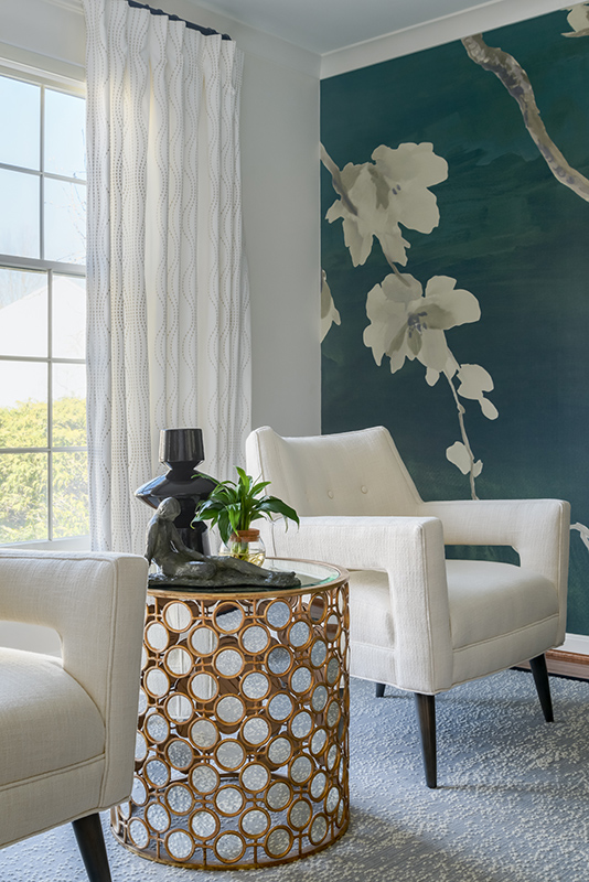 White armchairs and round rattan side table in front of bold teal floral mural, luxury home office interior design.