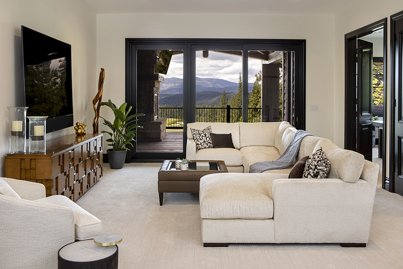 Stylish kid-friendly living room with cream sectional sofa, large TV, and mountain views through sliding glass doors.