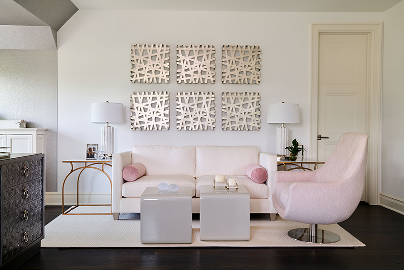Elegant modern living room with custom blush seating, white sofa, and geometric wall art designed by Impeccably Designed Homes.