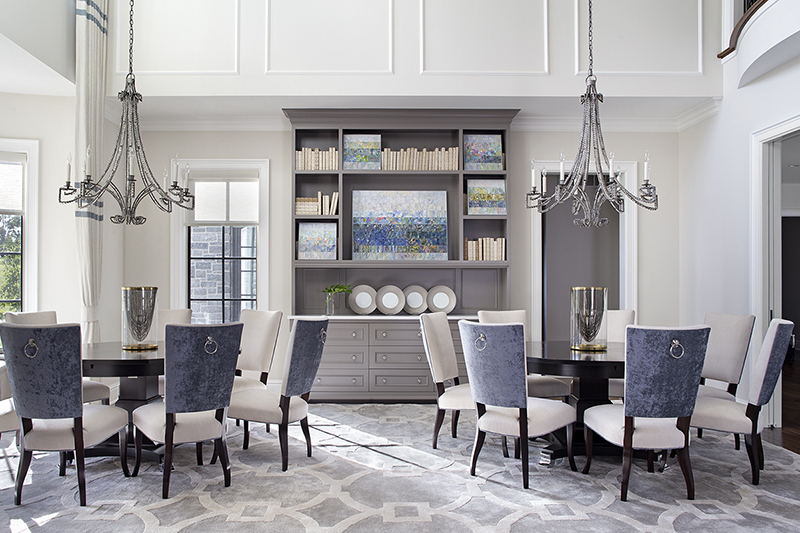 Luxury dining room with dual round tables, velvet chairs, and handcrafted built-in cabinetry by Impeccably Designed Homes.