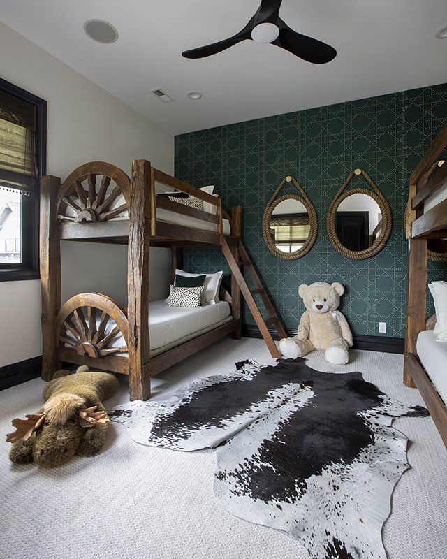 Chic bunk room with rustic wood beds, green grasscloth wallpaper, and playful accents – timeless interior design for kids’ spaces by IDH.