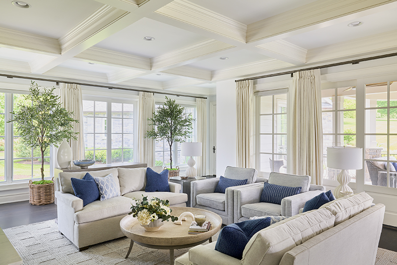 Neutral color palette interior design with layered neutrals, soft seating, indoor trees, and blue accent pillows creating a nurturing living space